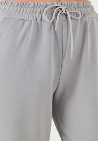 Graue Jogginghosen mit einem elastischen Bund und einem Kordelzug, seitlichen Taschen und einem weichen, strukturierten Stoff für zusätzlichen Komfort.