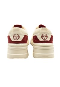 Balti sporta apavi ar sarkaniem zamšiem, teksturētām papēžu panelēm un apļa logotipu aizmugurē. Biezas gumijas zoles nodrošina stabilitāti.