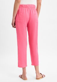 Roze linnenmix cropped broek met een elastische tailleband, twee achterzakken en een relaxte pasvorm, gecombineerd met lichtgekleurde sandalen.