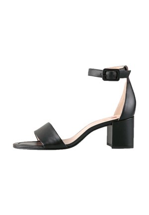 Sandal in pelle nera con una larga fascia per le dita, cinturino alla caviglia con fibbia e tacco a blocco spesso. Texture liscia e design minimal.