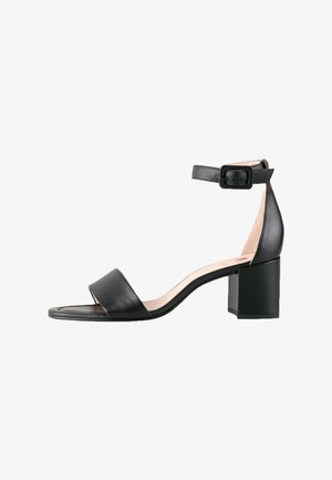 Sandal in pelle nera con una larga fascia per le dita, cinturino alla caviglia con fibbia e tacco a blocco spesso. Texture liscia e design minimal.