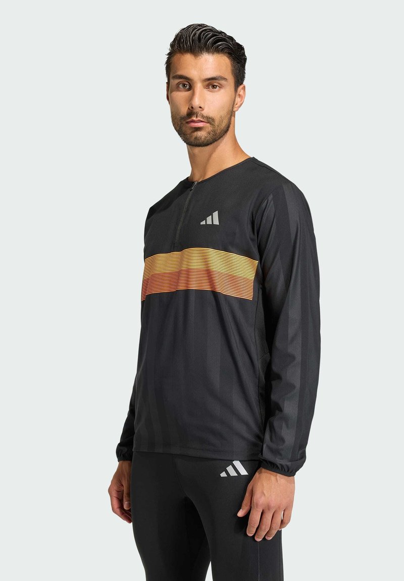 Black athletic long-sleeve top featuring a zipper, with an orange and yellow horizontal stripe across the chest. Logo on the left shoulder.