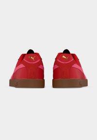 Κόκκινα αθλητικά παπούτσια με ροζ λεπτομέρειες, υλικά από σουέντ και δέρμα, και καφέ λαστιχένια σόλα. Διαθέτουν χρυσό λογότυπο στο πίσω μέρος.