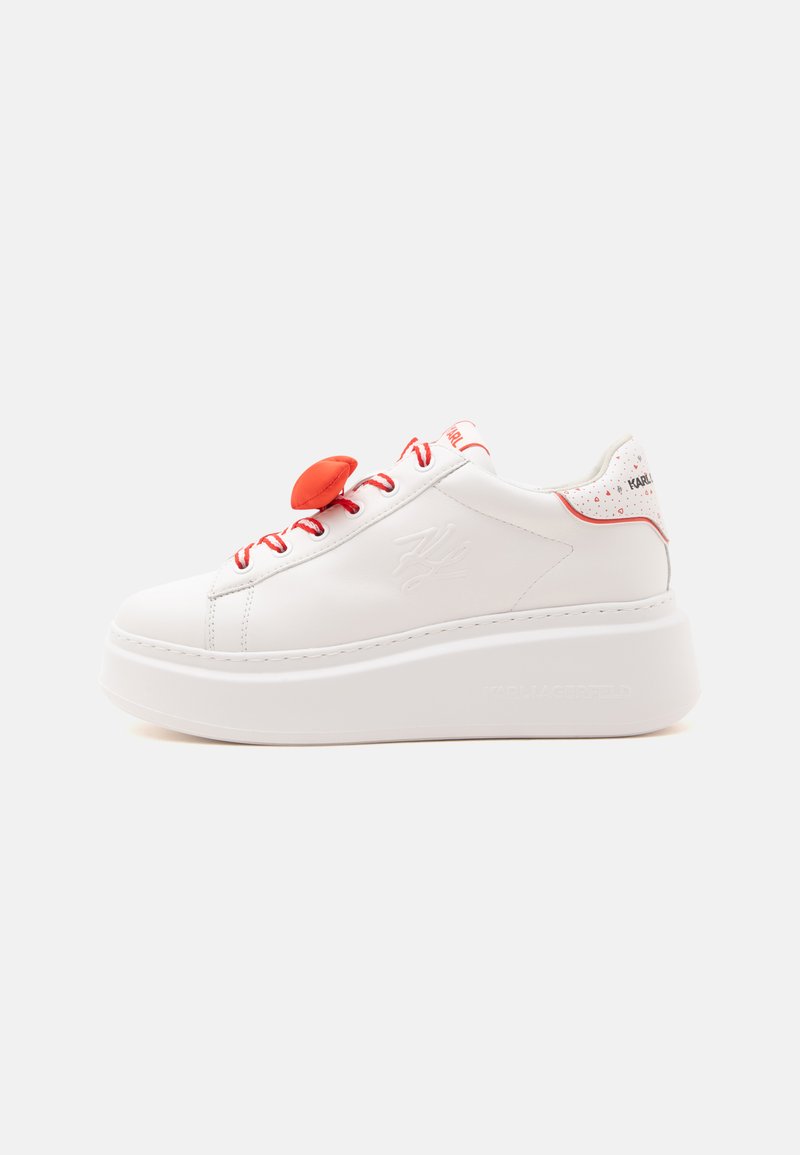 Λευκό πλατφόρμα sneaker με κόκκινες κορδόνια, κόκκινο αξεσουάρ κορδονιών σε σχήμα καρδιάς και κόκκινες λεπτομέρειες στη φτέρνα και τη γλώσσα.