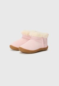 Bottines en daim rose avec un revers en fausse fourrure crème, dotées d'une semelle en caoutchouc brun flexible et de coutures le long des coutures.