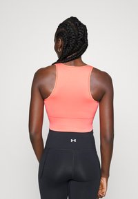 Top desportivo cor-de-rosa coral com um design ajustado, estilo costas nadador e textura canelada, combinado com leggings pretas de cintura alta com detalhe do logótipo.
