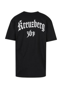Schwarzes Baumwoll-T-Shirt mit auffälligem weißen gotischen Text, der auf dem Rücken "Kreuzberg 361" liest, mit lockerer Passform und kurzen Ärmeln.