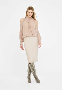 Hele roosa, voolav pluus volangkraega ja pikkade varrukatega, koos kreemja tekstuuriga seeliku ja põlvikute pikkuse krae-snake print saapatega.