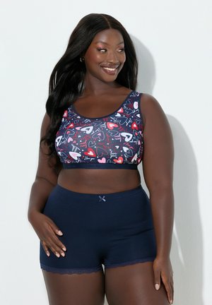 Námořnicky modrá podprsenka se vzorem srdcí v odstínech červené a bílé. K tomu ladící šortky s krajkovým lemem a malou mašličkou.