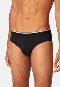 Schwarze Unterhosen aus glattem Baumwollmaterial mit einem kontrastierenden grauen Elastikbund. Sie verfügen über einen konturierten Beutel und Flachnähte für zusätzlichen Komfort.