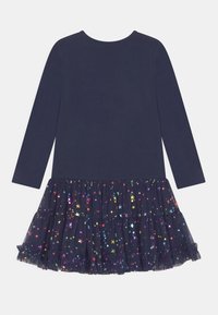 Robe bleu marine à manches longues avec une jupe en tulle superposée ornée de motifs d'étoiles colorées et un haut en tissu doux.