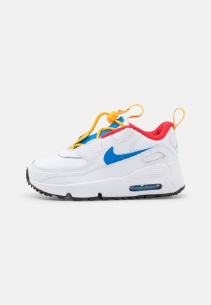 Biały but sportowy z niebieskim znakiem Nike, czerwoną podszewką, żółtą blokadą sznurowadeł i czarną podeszwą na jasnym, jednolitym tle.