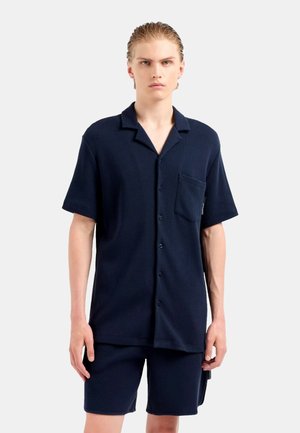 Marineblaues kurzärmeliges Hemd mit Tasche, durchgeknöpftem Vorderteil und strukturiertem Stoff, kombiniert mit passenden Shorts, beide in lockerer Passform.