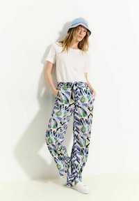 Pantaloni a taglio comodo, con motivo nei toni del blu, verde e viola. Tessuto di cotone con vita elasticizzata e cordoncino. Abbinati a una camicia bianca semplice e un cappello a secchiello.