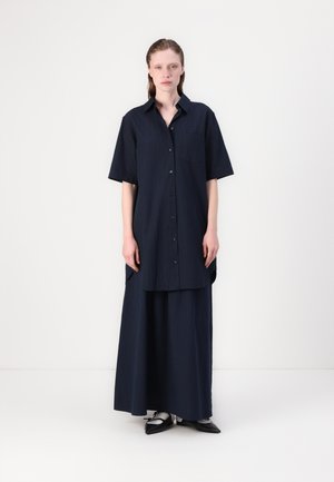 Dark navy shirt dress featuring short sleeves, a button front, a pocket, and a long flowing skirt. Smooth texture with subtle vertical stripes.