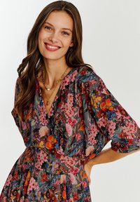 Sukienka florystyczna z szarym tłem i kolorowymi wzorami kwiatów. Dekolt w serek, krótkie rękawy i ściągnięta talia. Gładka faktura materiału.