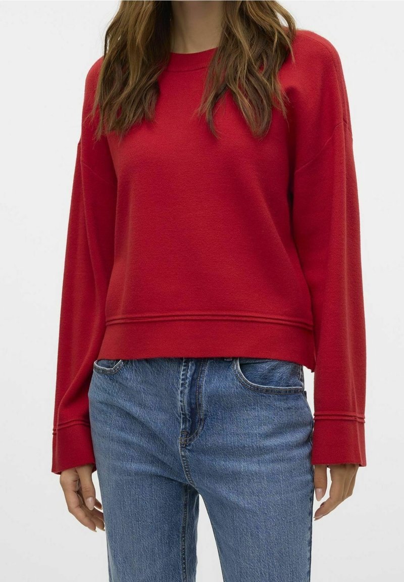 Sweat-shirt rouge à col rond, manches larges et coupe raccourcie. Confectionné en tissu texturé, il présente des détails cousus à l'ourlet.