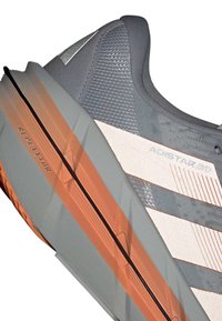 Grauer und orangefarbener Laufschuh mit strukturiertem Sohle, ausgestattet mit "ADISTAR BYD" und "REPETITOR" Branding an der Seite.