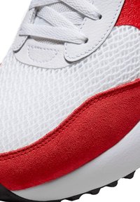 Sneaker alb cu accente din suede roșu, suprafață din plasă texturată, șireturi plate și talpă din cauciuc negru. Cusături vizibile pe margini.