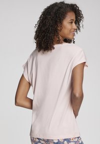 Hele roosa lühikeste varrukatega T-särk, millel on mugav lõige ja ümar krae, valmistatud pehmest kangast ning omab sileda tekstuuri.