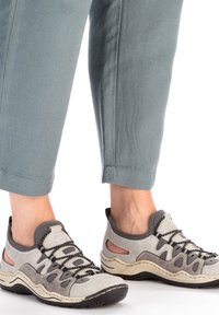 Gray and beige athletic shoes with mesh panels, textured surfaces, and a rounded toe. Laced with dark cords and a rubber sole.