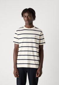 Stribet t-shirt i creme og marineblå bomuld, med rund hals, korte ærmer og lille logo detalje på brystet.
