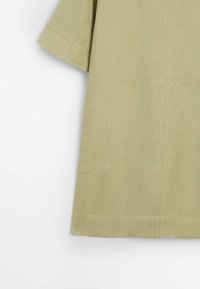 Robe verte kaki à manches courtes, confectionnée dans un tissu doux. Caractérisée par une coupe ample et des détails de couture subtils, avec des poches latérales discrètes.