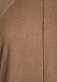 Hnedá pletená látka s hladkým povrchom, s jemným švom vedúcim vertikálne. Celkový odtieň je teplý a jednotný.