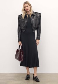 Veste en cuir noir courte avec épaulettes, robe midi noire, sac à main en simili croco bordeaux, et chaussures à talons blocs noires.