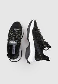 Baskets de sport noires avec tige en mesh, semelle texturée noire et blanche, lacets contrastants et accents réfléchissants. Motifs multicolores sur la tige.