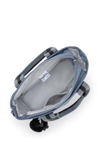 Borsa in tessuto grigio con chiusura a zip, manici a strisce e un portachiavi con pompon peloso. L'interno è foderato di grigio chiaro e presenta tasche.