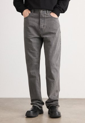 Gray denim jeans with a straight-leg fit, five-pocket design, and visible stitching. Worn with black slip-on shoes.