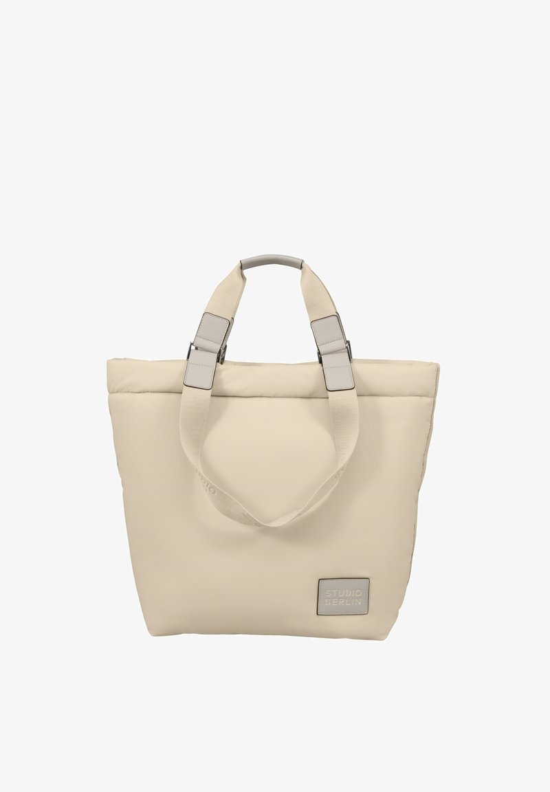 Krémová taška přes rameno s polstrovanou texturou a dvojitými uchy; má šedé kovové prvky a štítek s nápisem "STUDIO BERLIN" na přední straně.