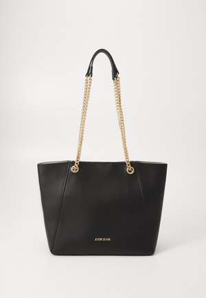 Black leather tote bag with gold chain handles, structured shape, and a logo on the front. Smooth texture with minimalist design.