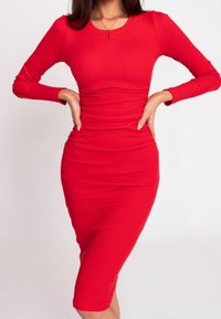 Robe longue à manches longues rouge à côtes, avec une silhouette ajustée atteignant le mollet. Texture lisse avec un col rond et des détails froncés à la taille.