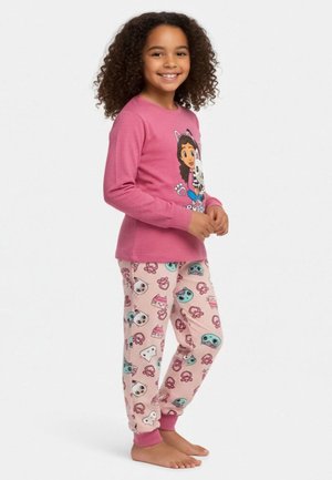 Mädchen mit lockigem Haar, das ein pinkfarbenes Langarmshirt mit Cartoon-Hundemotiv und passende Pyjamahosen mit verschiedenen bunten Tiergesichtern trägt.