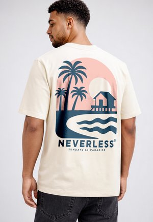 Man facing away wearing cream t-shirt with blue and pink sunset, palm trees, beach hut, and text "Neverless Sundays in Paradise."