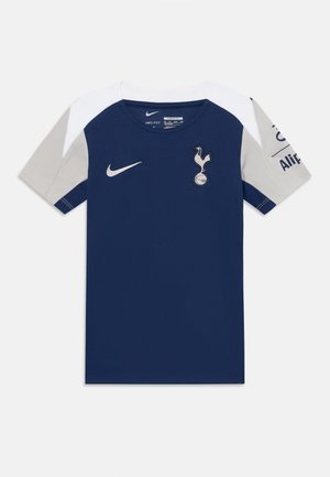 Tamsiai mėlynas futbolo marškinėliai su baltais ir šviesiai pilkais petukais, Nike logotipas ant krūtinės ir klubo herbas siuvinėtas priekyje.