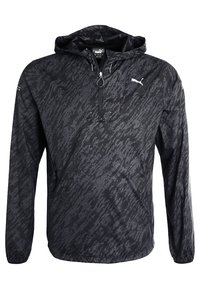 Chaqueta ligera negra con capucha y patrón texturizado, cierre de media cremallera y logotipo blanco en el pecho. Cuenta con mangas largas y un corte relajado.