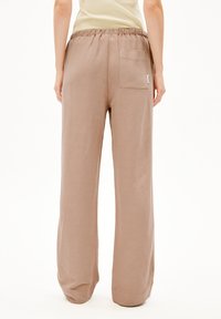 Hellbraune, locker sitzende Hosen mit weitem Bein, elastischem Taillenbund und einer einzelnen Gesäßtasche. Textil mit weicher Oberfläche.