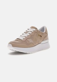 Sneaker beige chiaro in pelle con design perforato, lacci bianchi e suola bianca leggermente rialzata. Dettagli del logo dorati.