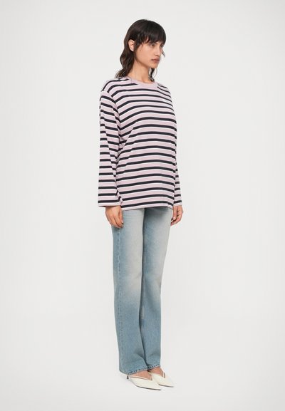 Röstripeeritud pika varrukaga särk helesinisest ja tumesinisest, millele on sobitatud helesinised laiad teksad ja valged terava ninaga kontsad.