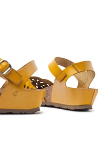 Yellow leather sandals with adjustable buckle, cork insole, and textured rubber sole. Cut-out pattern on sides for ventilation.