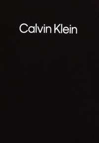 Svart bomullstyg med en slät yta som har vit texten "Calvin Klein" tydligt centrerad.