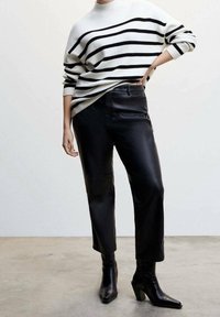 Sweter w biało-czarną striped, zestawiony z czarnymi skórzanymi spodniami i botkami o ostrej nosie na słupku.