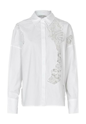 Hvit langermet bluse med blomsterlacedetaljer på venstre skulder, klassisk krage og knappelukking foran. Myk bomullsstoff.