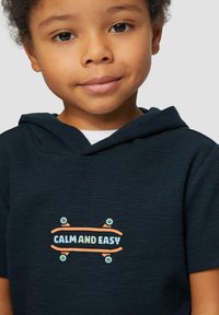 Donker marineblauwe hoodie met een textuurstof. Heeft een kleurraf skateboardafbeelding met de tekst "CALM AND EASY" in het midden.
