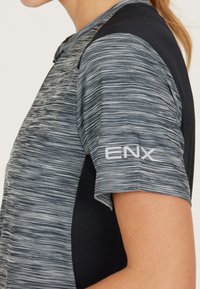 Grå och svart sporttröja med en texturerad mönster, som har ett ventilerande tyg och logotypen "ENX" på ärmen.
