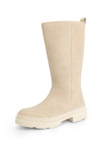 Beige suède laarzen tot halverwege het kalf met een robuuste rubberen zool en gestikte details, met een lus aan de achterkant, gepresenteerd op een witte achtergrond.