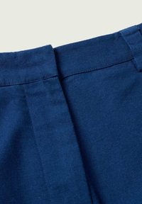 Dunkelblauem Stoff mit strukturiertem Finish, ausgestattet mit einem sauberen Bund und subtilen Faltendetails, entworfen für einen eleganten, maßgeschneiderten Look.